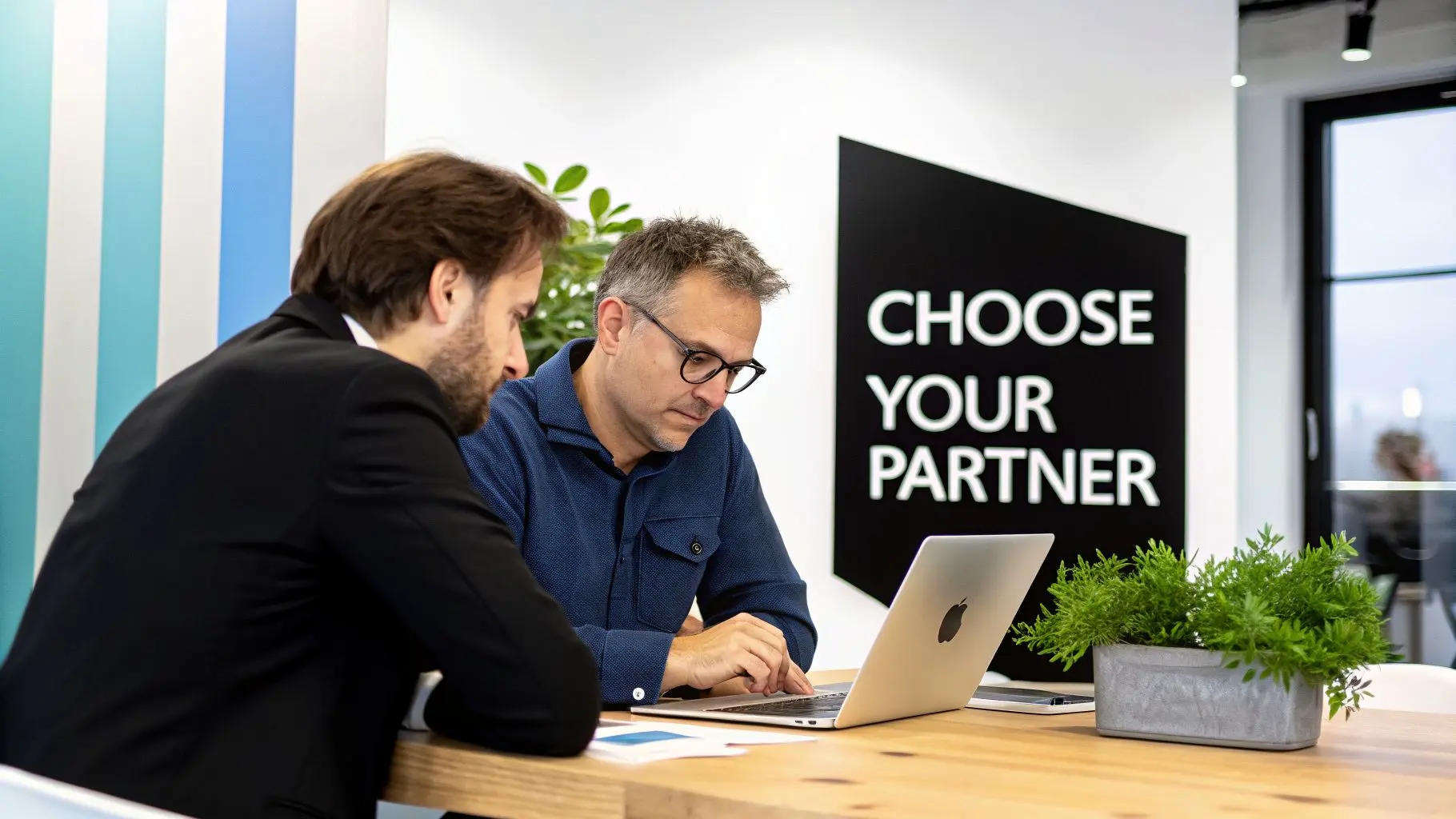 Two business professionals collaborating on a laptop in a modern office environment.
