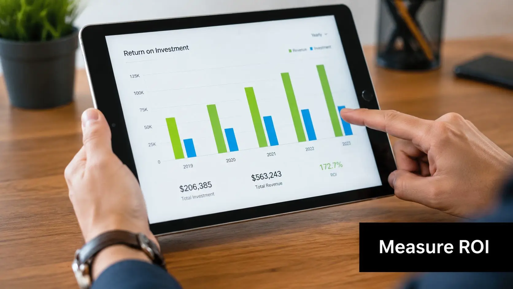 A person holding a tablet showing a bar chart of Return on Investment data on a desk.
