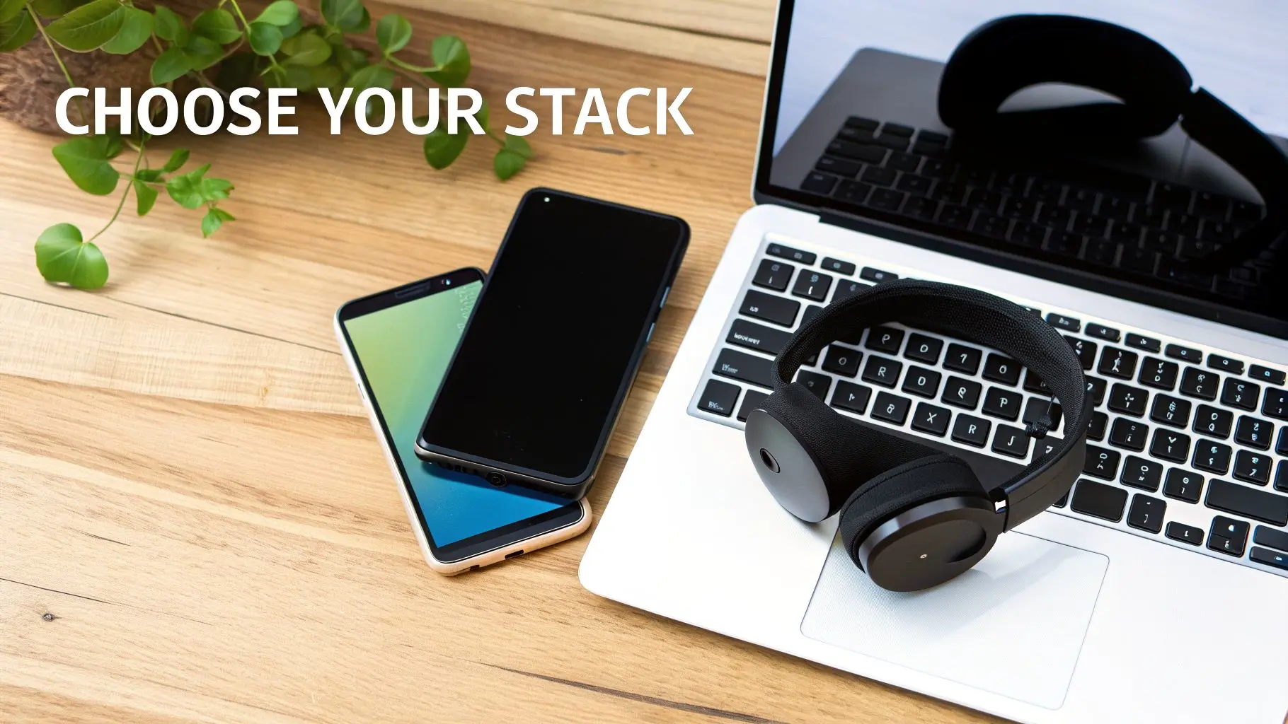 Overhead view of a laptop, two smartphones, headphones, and a plant on a wooden desk. Text 'CHOOSE YOUR STACK'.