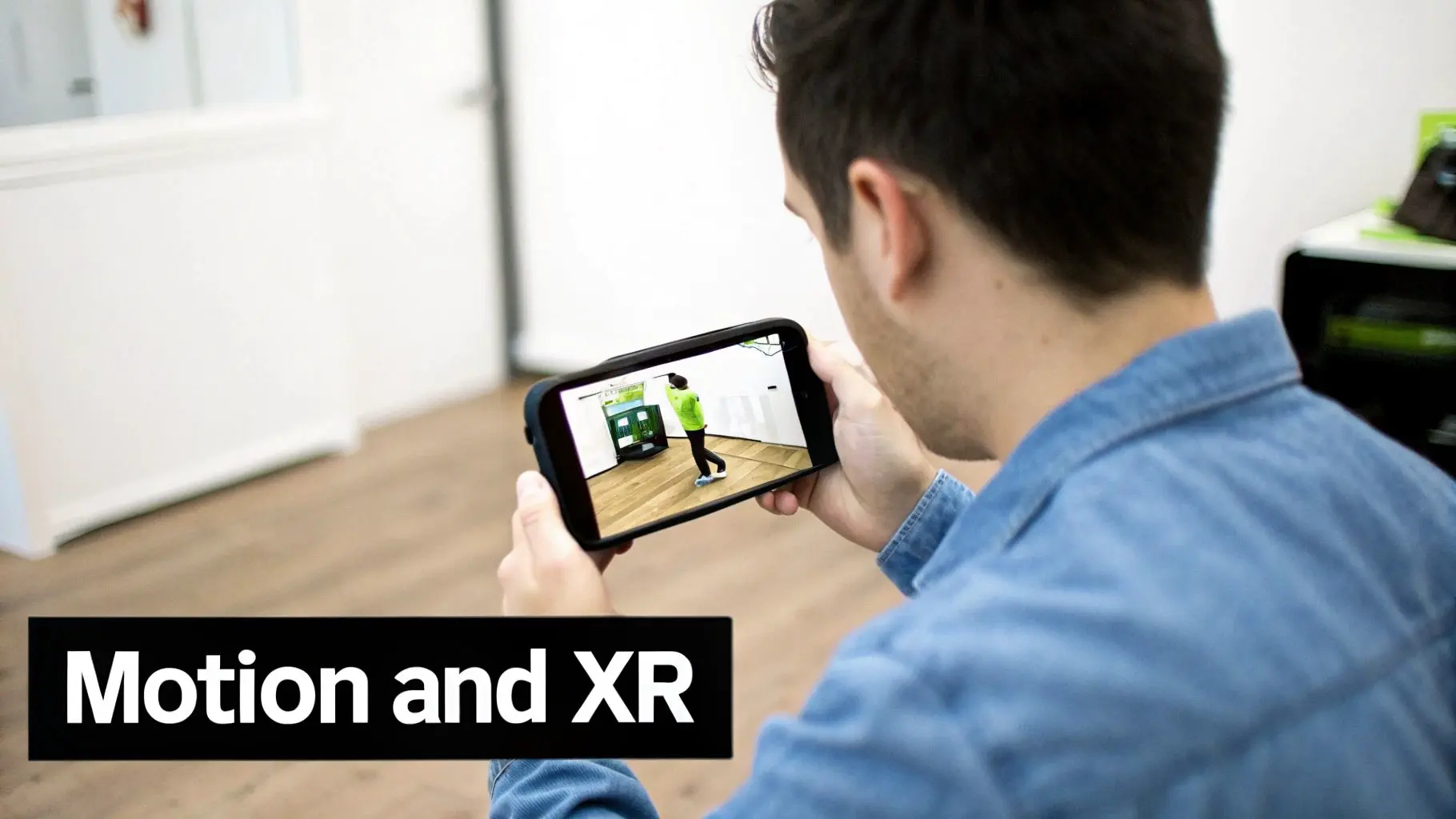 A man in a denim shirt holds a smartphone horizontally, displaying a motion-based XR application.